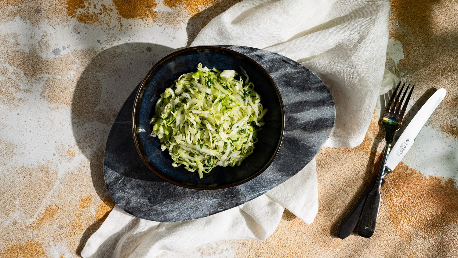 Coleslaw with fresh herbs served in a dark bowl.